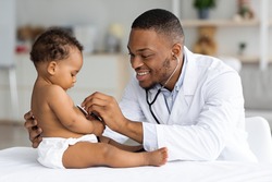 Black Male Pediatrician Listening Infant Child's Heartbeat With Stethoscope During Checkup At Home, Smiling African American Pediatrist Doctor Checking Baby's Heart And Lungs, Closeup Shot