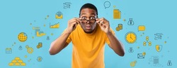 Shocked African American guy looking at camera through glasses, expressing surprise on blue studio background, collage with business, money and finance pictograms. Financial literacy concept. Panorama