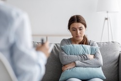 Sad european young woman suffering from depression and consults with psychologist in clinic, empty space. Mental therapy, survive personal crisis, individual counselling, problems and treatment