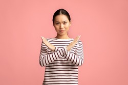 Refusal. Young Asian Woman Showing Stop Gesture With Crossed Hands, Serious Millennial Korean Female Refusing Something Unwanted While Standing Isolated Over Pink Studio Background, Copy Space