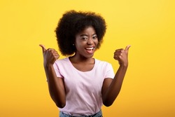 Best choice. Happy african american lady showing thumbs up gesture with both hands, approving or recommending something good, posing isolated on yellow studio wall, banner