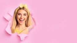 Smiling happy pretty millennial caucasian blonde lady with open mouth look through hole in pink paper, empty space, collage, panorama. Positive facial expression, good offer, sale and people emotions