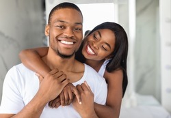 Portrait Of Happy Young Black Spouses Embracing In Bathroom Interior, Loving Young African American Couple Having Fun Together While Making Morning Beauty Self-Care Routine At Home, Closeup Shot
