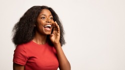 Positive Young Black Woman With Hand Near Mouth Making Announcement, Cheerful African American Female Sharing News Or Information While Standing Isolated On White Background, Panorama, Copy Space
