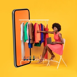 Mobile Shopping. African American Woman Sitting Near Big Cellphone Choosing Clothes On Rail And Buying Online Using Laptop On Yellow Studio Background. E-Commerce Concept. Collage