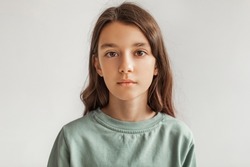 Portrait Of Serious Preteen Girl Standing Looking At Camera Over Gray Studio Background. Calm Kid Posing Wearing Casual Clothes, Headshot. Children Fashion Concept. Front View