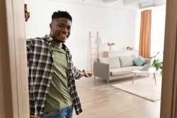 Welcome To My House. Cheerful Black Man Opening Door And Gesturing Inviting To Come In And Showing His Living Room Smiling To Camera Standing At Home. Real Estate Ownership And Hospitality
