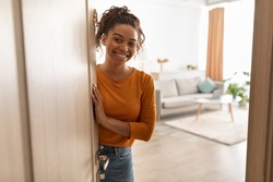 Joyful African American Female Opening Door And Smiling To Camera Standing At Home. Friendly Lady Meeting You In Doors Of Her House. Real Estate Property Ownership Concept
