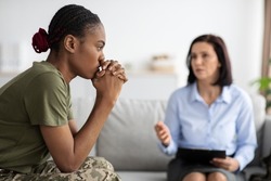 Upset Pensive Black Military Lady Having Therapy Session With Psychologist In Office, African American Soldier Woman Suffering Mental Illness Or Posttraumatic Stress Disorder, Selective Focus