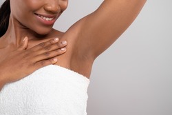 Hair Removal Concept. Unrecognizable Black Female Demonstrating Her Armpit With Smooth Skin, Smiling African American Woman Wrapped In Bath Towel Standing Over Grey Background, Copy Space