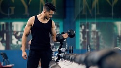 Bodybuilding Concept. Portrait Of Muscular Young Arab Man Training With Dumbbells At Gym, Confident Middle Eastern Bodybuilder Working Out With Light Weights In Sport Club, Panorama, Copy Space