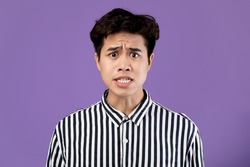 People, Human Emotions And Feelings Concept. Portrait of shocked scared Asian man looking staring at camera in amazement, sad male isolated over purple violet studio background wall