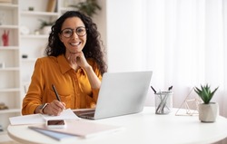 Happy Brunette Business Lady Using Laptop Smiling To Camera Posing Wearing Glasses Working Sitting At Workplace In Modern Office. Successful Entrepreneurship And Career Concept