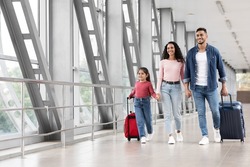 Travel Advertisement. Portrait Of Happy Arab Family Walking With Luggage At Airport, Beautiful Middle Eastern Mother, Father And Little Daughter Going To Boarding, Enjoying Traveling Together