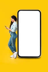 Cheerful Casual Lady Leaning On Big Giant Smartphone With Empty White Display, Smiling Female Holding Using Cell Phone, Browsing Website Testing App, Mock Up, Full Body Length Banner Profile Side View