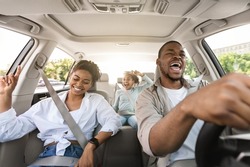 Joyful African American Family Riding New Car Singing And Having Fun During Summer Road Trip. Parents And Daughter Traveling By Auto On Weekend. Transportation. Selective Focus