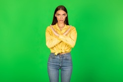 Refusal. Serious Woman Gesturing Stop Crossing Hands Looking At Camera Forbidding Something Standing Over Green Studio Background. No, I Don't Agree. Rejection Concept