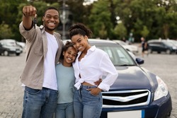 Joyful Black Family Showing New Car Key Posing Standing Near Luxury Auto Outdoor, Smiling To Camera. Parents And Daughter Celebrating Buying Vehicle. Automobile Leasing And Ownership