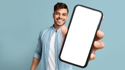 Smiling Handsome Arab Guy In Casual Showing Mobile Phone With White Blank Screen For Advertisement, Recommending Mobile Dating Application, Panorama With Free Space, Mockup, Colllage
