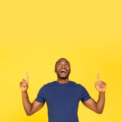 Excited  Man Pointing Fingers Up Advertising Great Offer Standing Over Yellow Studio Background. Look Upward Concept. Advertisement Banner, Square Shot
