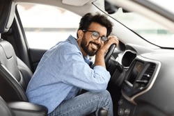 Automobile renting, buying, leasing. Thrilled young indian guy hugging steering wheel of his brand new car. Happy eastern man auto owner enjoying vehicle, lean on wheel with closed eyes and smiling