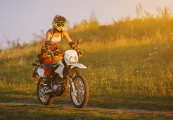 Woman biker rides in fields. Sporty woman biker at motobike. Countryside, country road.  sunset, female motorcycle rider, motorbike rider traveling the world, girl resting, freedom lifestyle
