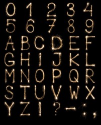 Full english alphabet and numbers set made from burning sparkles on black background. Shiny festive firework latin font.