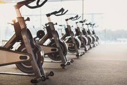 Modern gym interior with equipment. Row of training exercise bikes detail, backlight. Healthy lifestyle concept