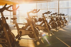 Modern gym interior with equipment. Fitness club with training exercise bikes in evening backlight.