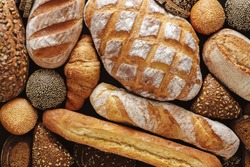 Bread background, top view of white, black and rye loaves on black