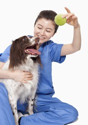 Portrait of female veterinarian holding a ball with a dog
