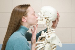 Female student kissing a human skeleton