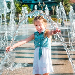 little  girl having fun in splashes a fountain