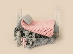 Newborn baby studio furniture bed for infant child photoshoot decorated with knitted toys. Tiny designed scene for kid studio portrait with pillow and blanket