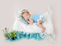 Adorable newborn baby girl sleeping in tiny bad. Sweet infant child kid wearing dress and wreath napping