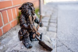Dwarf with a padlock near bridge. Small bronze figures of gnomes on the streets of Wroclaw. Europe