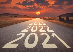 2021 2022 and 2023 new year written on highway as future and success concept against the happy looking sunset.