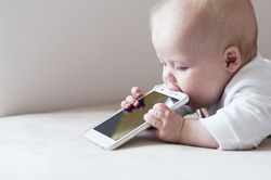 The teething baby is biting a cell phone