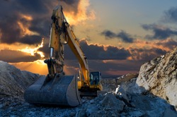 Image of a tracked excavator in a quarry with a setting sun and light rays