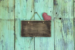 Blank wood sign with rope heart hanging on antique rustic mint green wooden door; Valentine's Day and love concept background with painted copy space