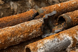 Fragments of old cast-iron water pipes. After many years of operation corroded metal pipe was destroyed. Rusty steel tube with holes of metallic corrosion. Rusty cast iron, metal