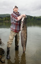 A happy fisherman presenting his fishing trophy caught in a Polish lake - catfish (Silurus glanis)