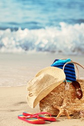 Closeup of summer beach bag with items on sandy beach