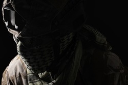 Photo of a military soldier fully equipped face in helmet, glasses and uniform on black background.