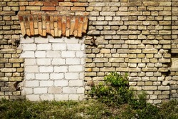 Old abandoned wall with bricked up windows. Architecture detail background. Forgotten building of plaster and red brick