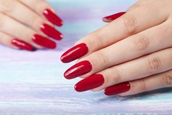 Hands with long artificial manicured nails colored with red nail polish 