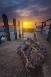 The sun goes down over a lone lobster pot by a slipway