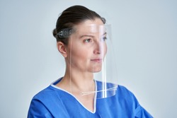 Close up portrait of female medical doctor or nurse wearing face shield