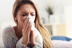 Picture showing sick woman sneezing at home