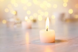 Small candle with light yellow spots on light background